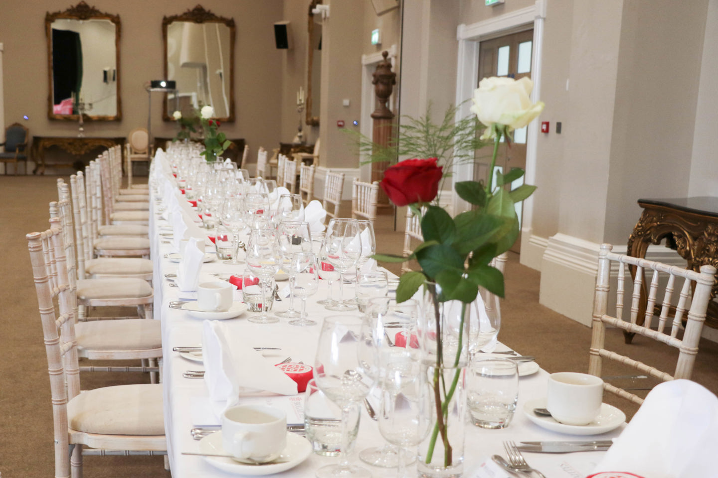 Long table setup for a private function, with red flower decoration