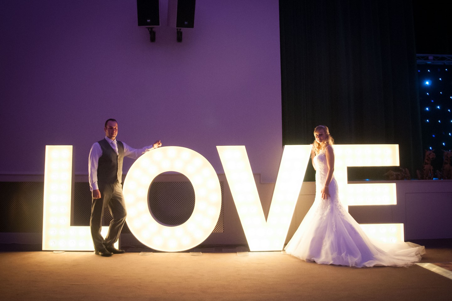 Bride and groom in front of light up love letters