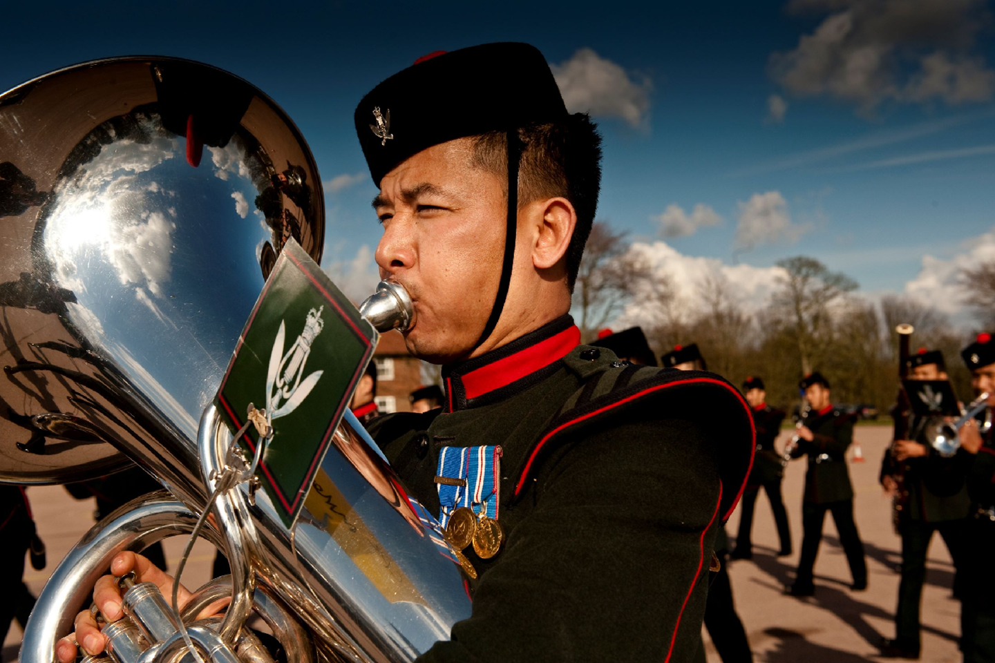 Gurkha soldier performing with a tuba at a ceremony 