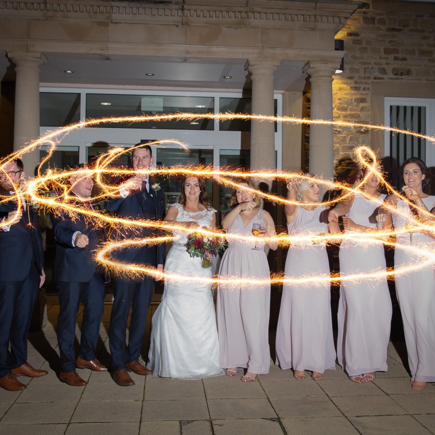 Wedding party with sparklers in front of the building