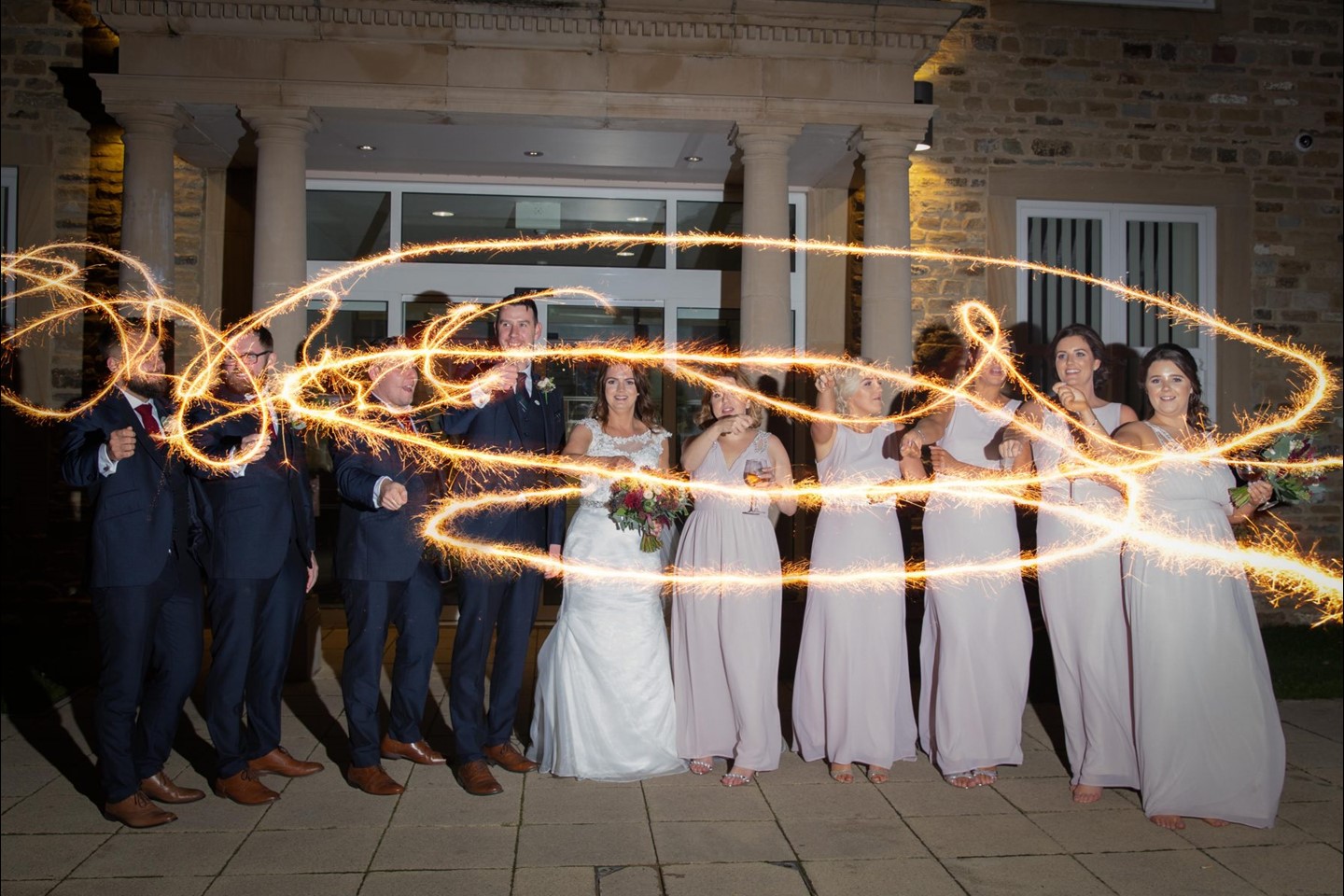 Wedding party with sparklers in front of the building