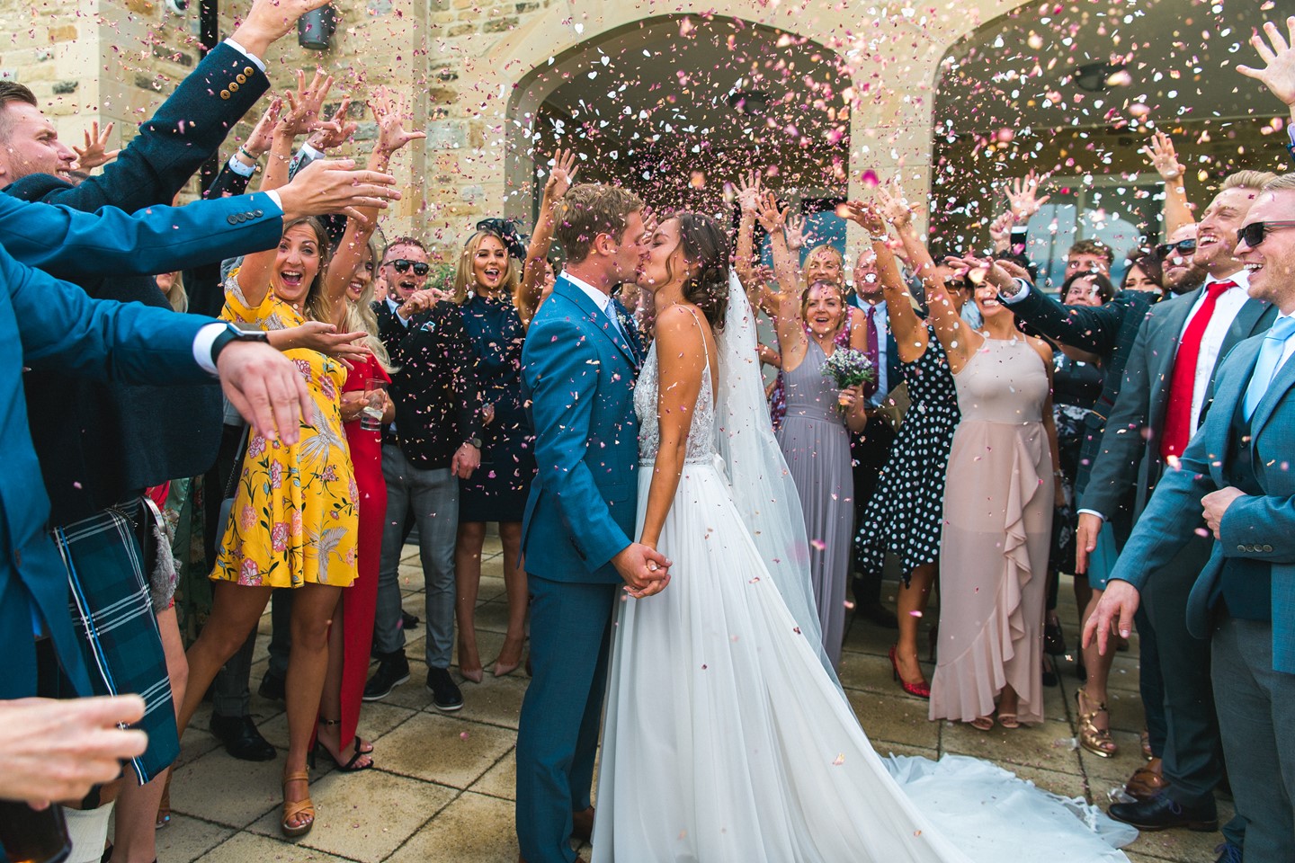 Bride and groom surrounded by confetti and wedding guests